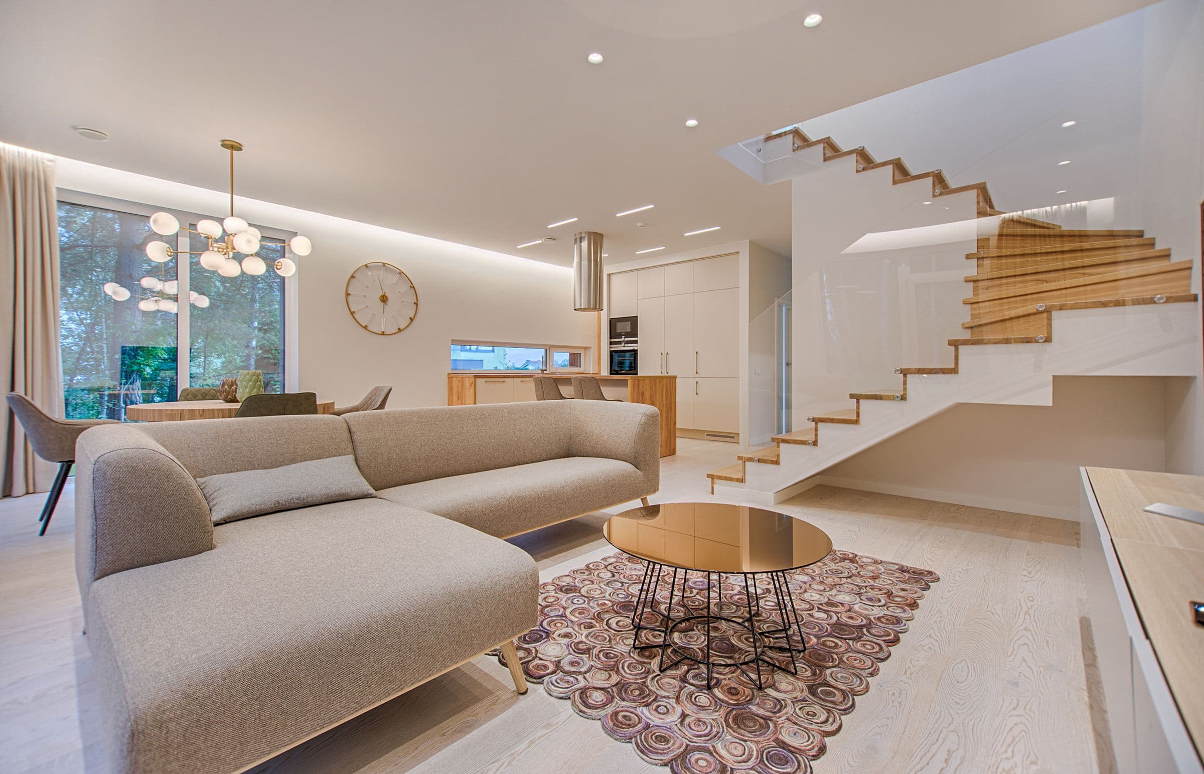 Sunlit open living room with a light sectional, dining table, and kitchen beyond
