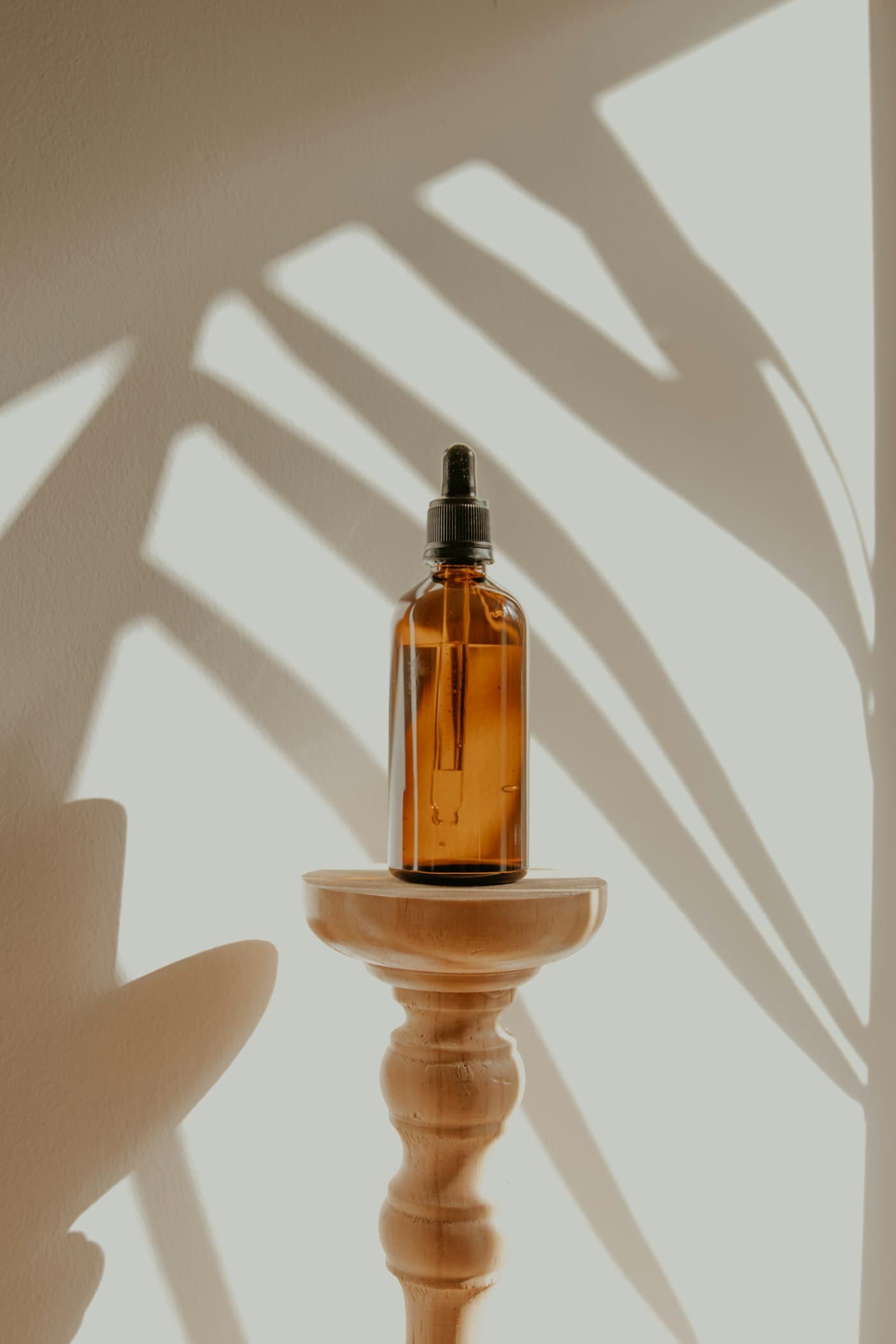 Still life of an amber glass bottle on a wooden pedestal